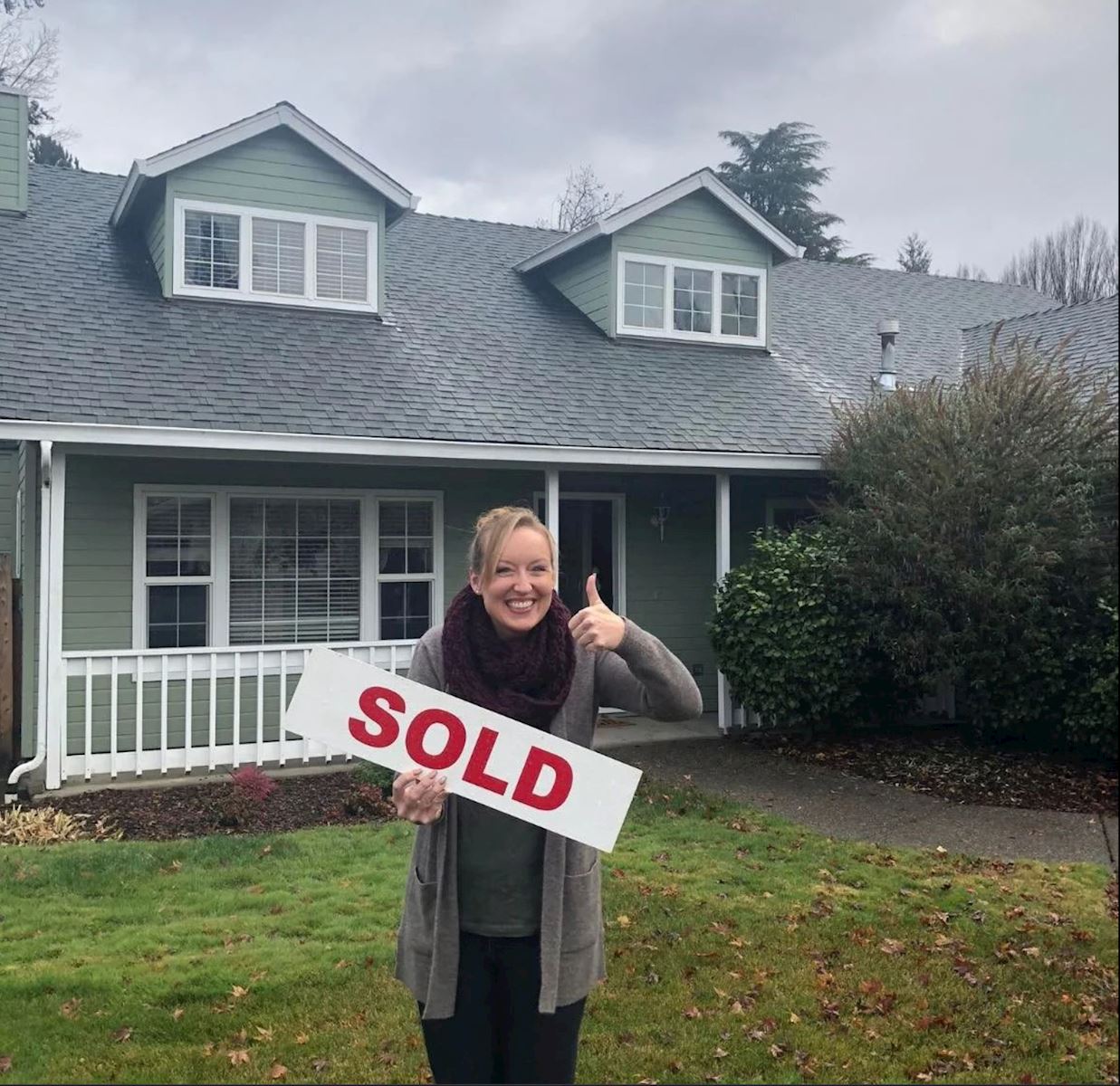 Woman Holding SOLD Sign in front of house