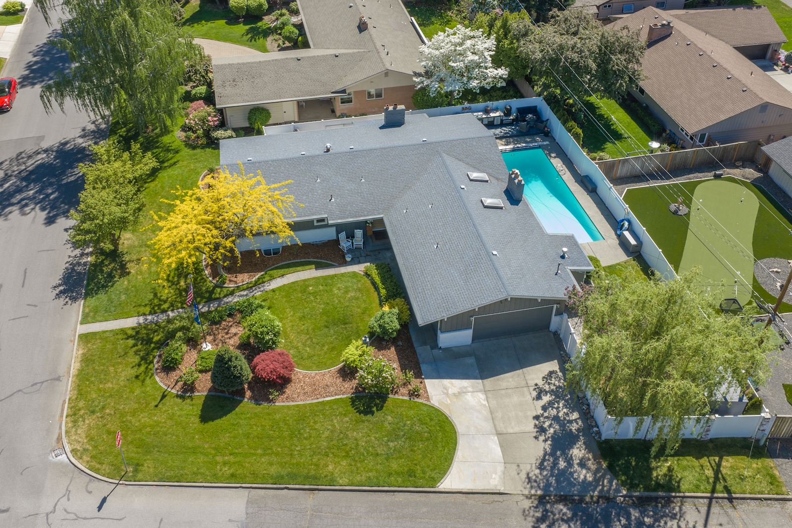 Front exterior drone view of 4206 S Pittsburg St Spokane WA 99203, a fully updated South Hill midcentury modern rancher with landscaped corner lot, pool, and outdoor entertaining spaces