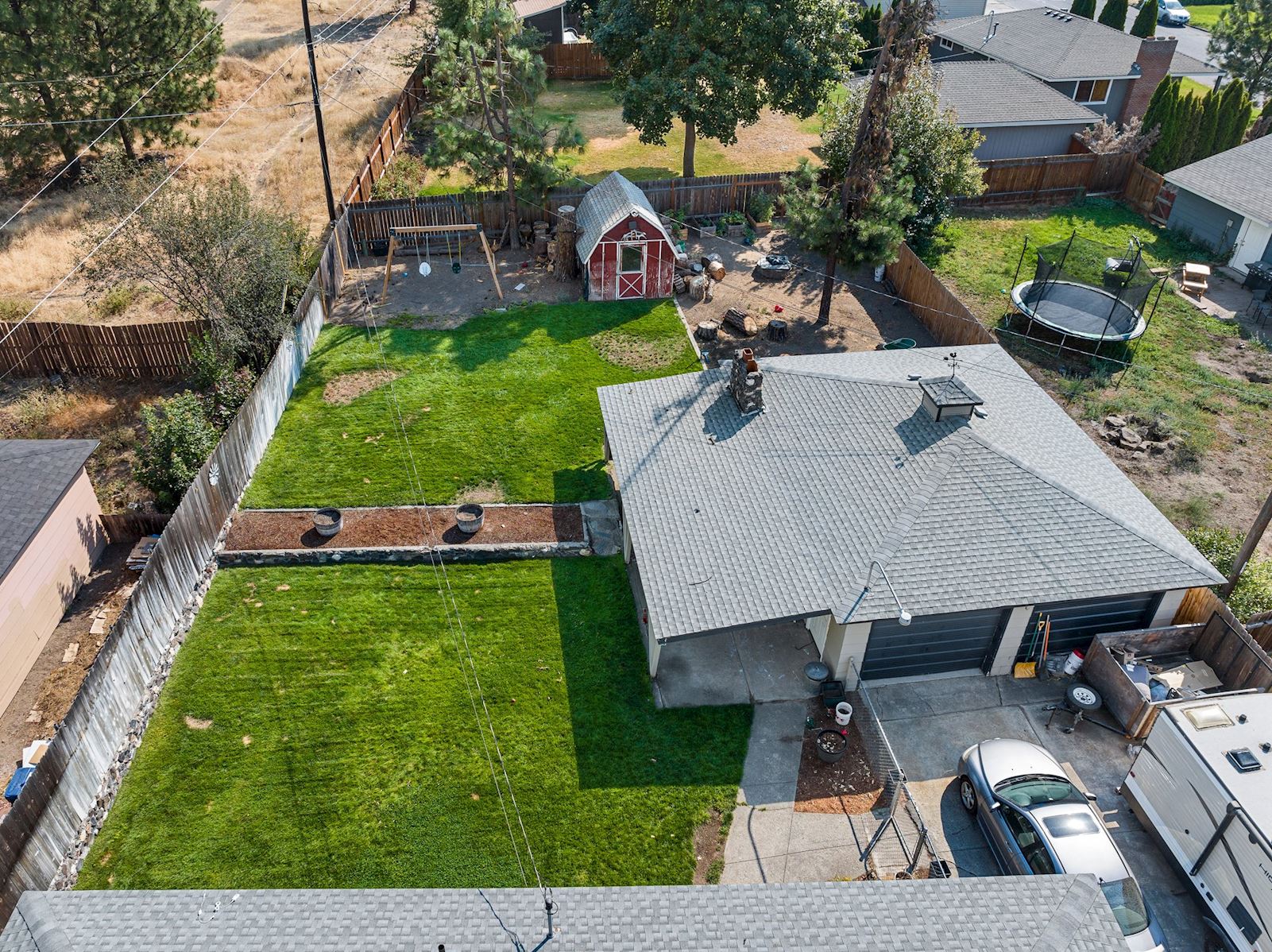 Fully fenced backyard showcasing the lawn and oversized shop at 6516 N Hartley St in North Spokane WA 99208. Real estate listing by Team Dailey | John L. Scott Real Estate.